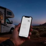 Satellite texting for RVers: a hand holds a smartphone toward the night sky beside a motorhome at a desert boondocking site